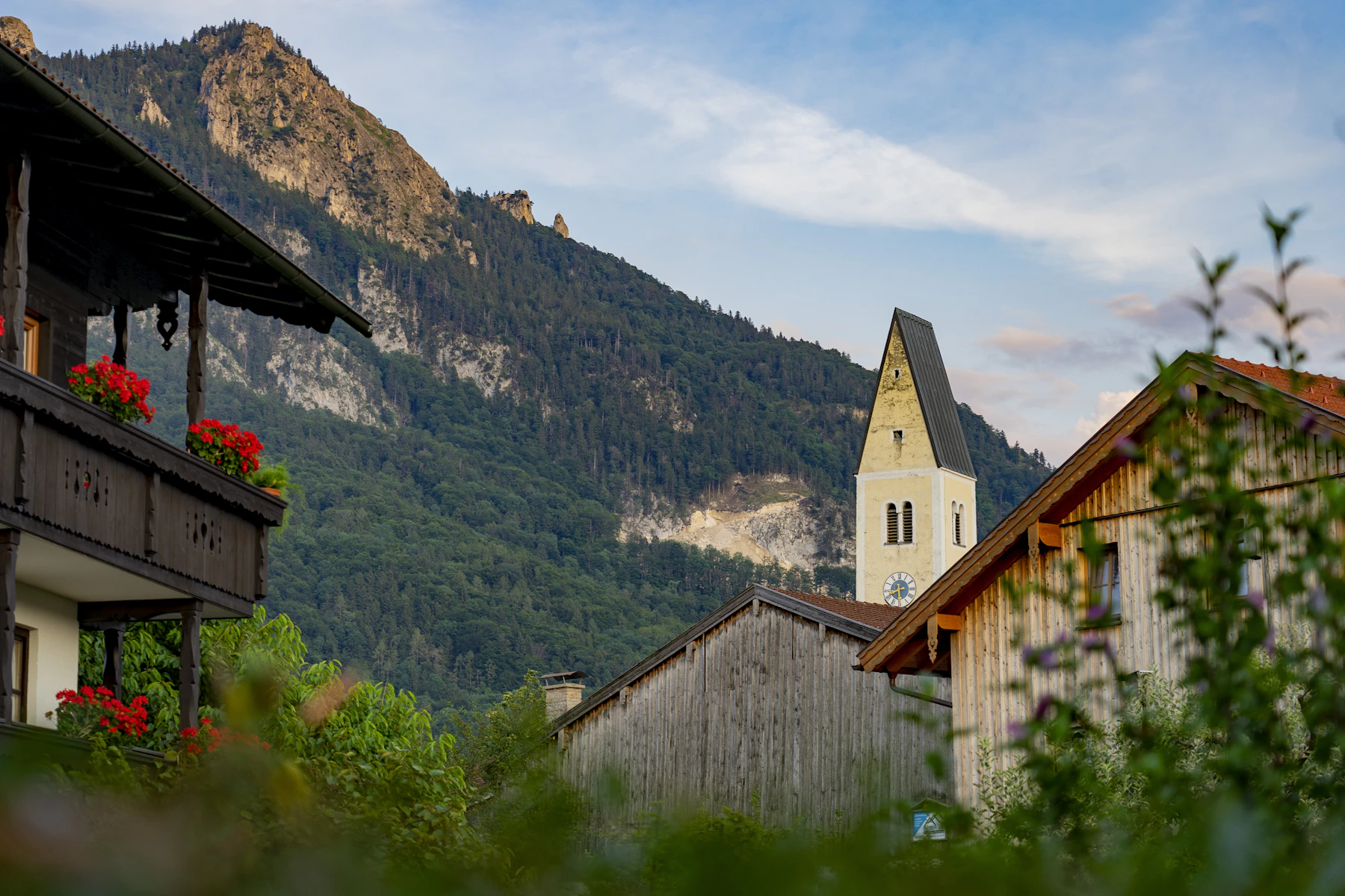 A village church with flower boxes below steep alpine peaks