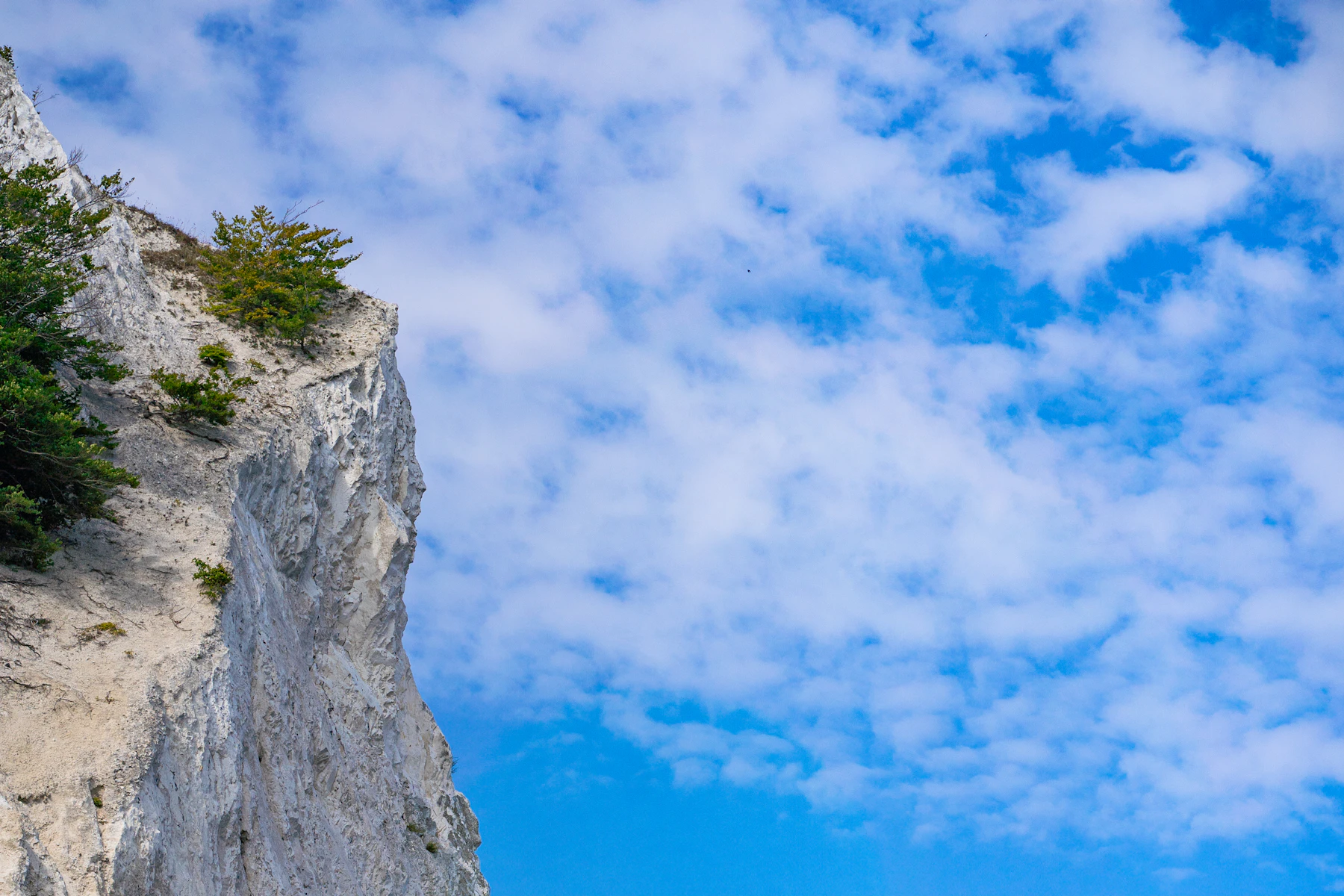 A white chalk sea cliff under a bright sky