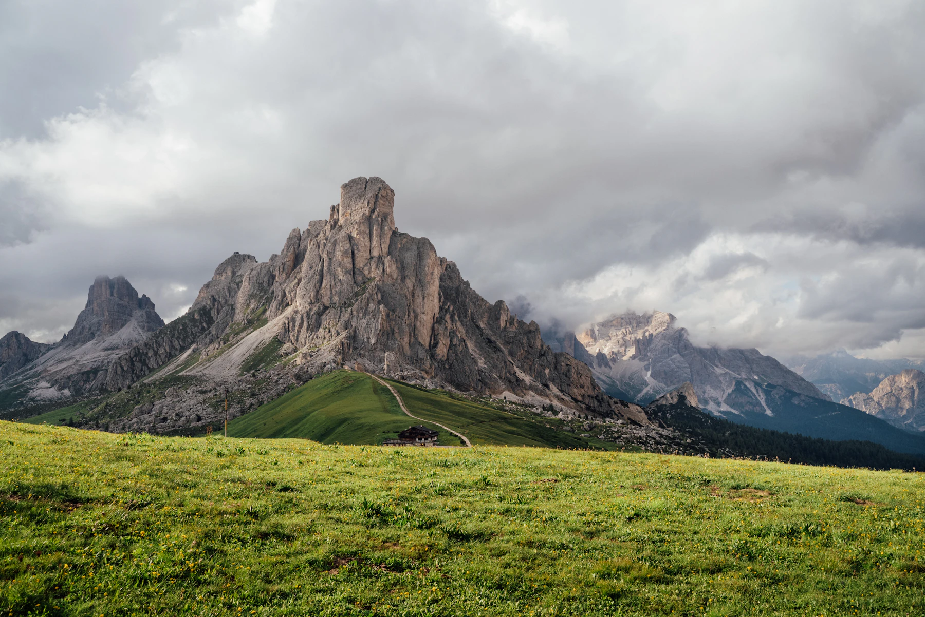 A green alpine meadow below a rocky Dolomite peak